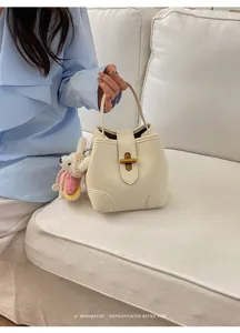 Dettaglio borsa a secchiello minimalista, pelle bianca elegante con serratura in metallo.