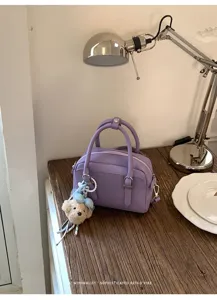 Vue rapprochée du sac Boston en cuir violet avec un joli pendentif ours en peluche.