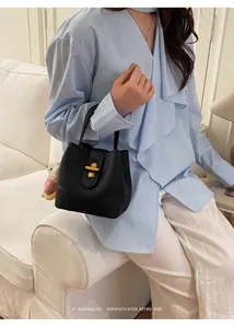 Borsa a secchiello nera chic in pelle con chiusura dorata da donna minimalista.
