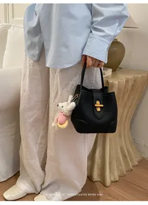 Dettaglio ravvicinato di una borsa a secchiello nera minimalista con chiusura in metallo.