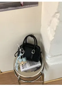 Gros plan sur les détails du sac Boston en cuir noir avec joli pendentif ours tabouret.