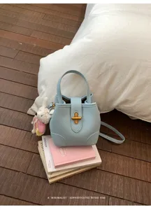 Elegante borsa a secchiello in pelle azzurra con manico e tracolla, stile retrò chic.