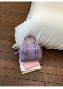 Gros plan d'un sac bandoulière Boston lavande en cuir texturé avec des détails de boucles.