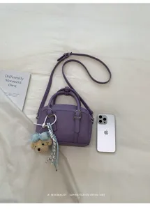 Détail du sac Boston en cuir violet montrant un design élégant, une bandoulière et un charm.