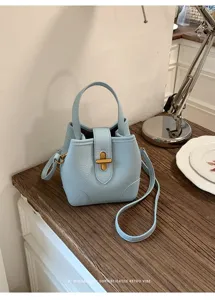 Dettaglio ravvicinato della borsa a secchiello in pelle azzurra con chiusura metallica.