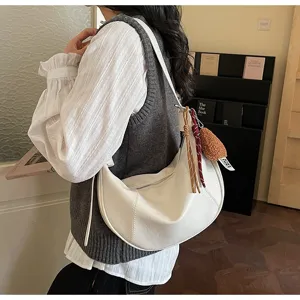 Detailed view of white hobo crescent bag with charms, shoulder wear scene indoor.