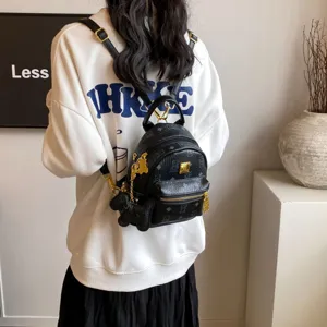 Vista dettagliata di un chic mini zaino nero in pelle con ciondoli a orsetto e finiture dorate.