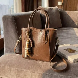 Elegant brown vintage women tote bag with shoulder strap and chic wooden bead pendant accessory.