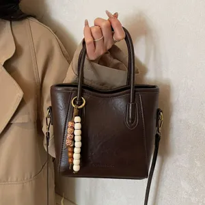Elegant dark brown leather tote bag for women, stylish retro crossbody commuting handbag.