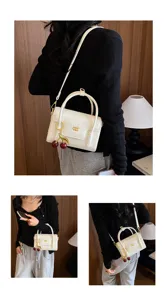 Detail shot of white crocodile pattern crossbody bag with cherry charm and gold hardware.