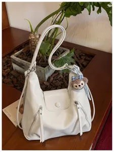 Borsa a spalla hobo in ecopelle bianca con tasche frontali con zip e ciondolo peluche.