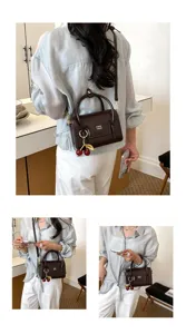 Detailed view of women crocodile texture crossbody bag with cherry charm and top handle.