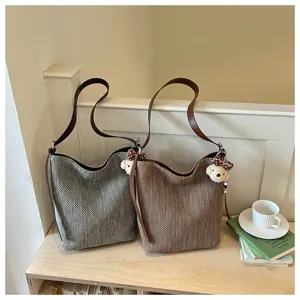 Grande borsa a tracolla intrecciata da donna, elegante borsa a secchiello autunnale con simpatico ciondolo.