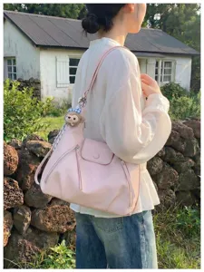 Vista dettagliata della elegante borsa a spalla rosa con tasche con zip e ciondolo.