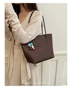 Primo piano della borsa a spalla in pelle intrecciata marrone scuro con dettagli artigianali.