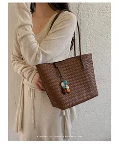Dettaglio borsa shopper intrecciata retrò in pelle, grande borsa a spalla con ciondolo.