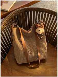 Vista dettagliata della grande borsa intrecciata con cinturini in pelle marrone e ciondolo cucciolo.
