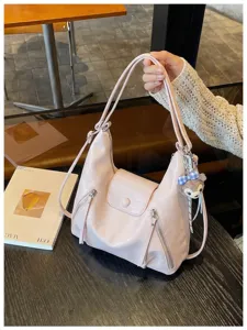 Vista di dettaglio della borsa rosa chiaro con tasche con zip e grazioso ciondolo in peluche.