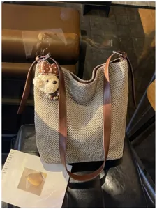 Dettaglio della grande borsa a secchiello in tessuto con cinturini in pelle marrone e ciondolo cane.