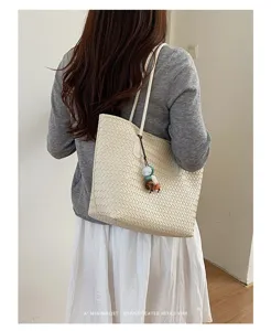 Primo piano di una borsa tote intrecciata beige, che mette in risalto la trama e i dettagli.
