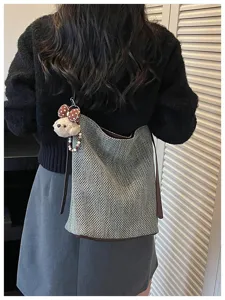 Dettaglio borsa a secchiello intrecciata, elegante borsa a tracolla con ciondolo per uso quotidiano.