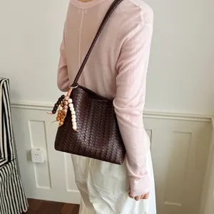 Sac à bandoulière tressé pour femme, sac seau souple et élégant avec pendentif en perles chic.