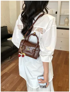 Brown crocodile pattern women handbag stylish crossbody bag with cherry charm and top handle.