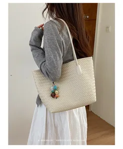 Vista dettagliata della borsa tote intrecciata da donna con ciondolo in stile retrò minimal.