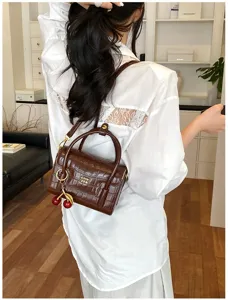 Detailed back view of brown crocodile pattern crossbody bag with cute cherry charm and hardware.