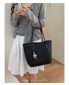 Dettaglio della borsa shopper intrecciata retrò in pelle nera con ciondolo di perline.