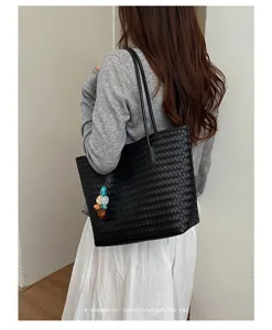 Primo piano della borsa tote in pelle intrecciata nera che mostra dettagli artigianali e texture.
