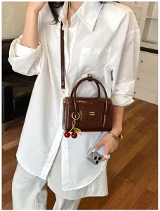 Brown crocodile pattern crossbody bag with cherry charm, stylish small handbag for women.