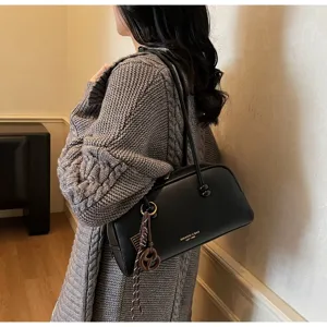 Detail shot of a sleek black leather bowling shoulder bag with dual handles and chic charm.