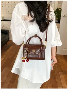 Stylish brown crocodile pattern small handbag with handle and cherry charm for daily wear.