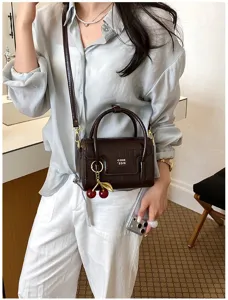 Detailed view of chic dark brown crocodile pattern crossbody bag featuring cherry charm.