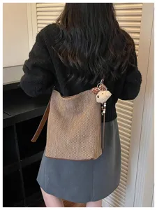 Primo piano della borsa a secchiello intrecciata da donna che mostra trama e cinturino autunnale.