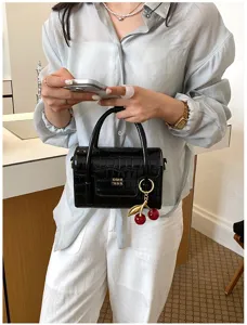 Black crocodile pattern handbag for women, chic crossbody bag with cute cherry charm accessory.
