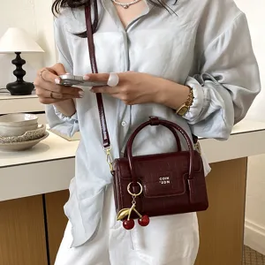 Burgundy crocodile pattern handbag with cherry charm, stylish women's crossbody bag for daily.