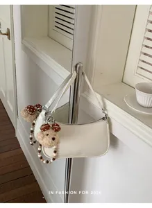 White underarm shoulder bag with cute bear charm, stylish niche design for women's spring fashion.