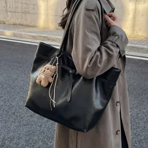 Large capacity women's black PU leather tote bag with cute bear pendant for daily commute.