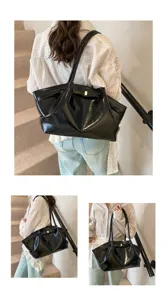 Detailed view of the black glossy shoulder bag showcasing pleats and gold metal clasp.