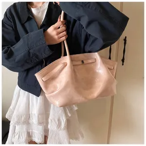 Close-up of pink crinkled leather tote bag, soft texture and chic shoulder design.
