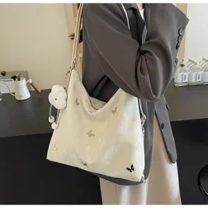 Close-up of the cream shoulder tote bag featuring delicate butterfly details and a plush cloud charm.