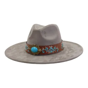 Detalle del sombrero Fedora gris de ante con banda de cuero bordada marrón y hebilla turquesa.