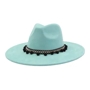 Close-up detail of light blue faux suede fedora hat featuring black pom-pom woven band.