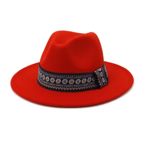 Gedetailleerde opname van de rode wollen fedora hoed met een stijlvolle blauwe etno band.