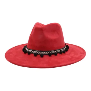 Detailed view of the red suede fedora hat featuring a black white woven band and cute pom poms.