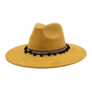 Detailed showcase of yellow suede fedora hat featuring black white band and pom poms.