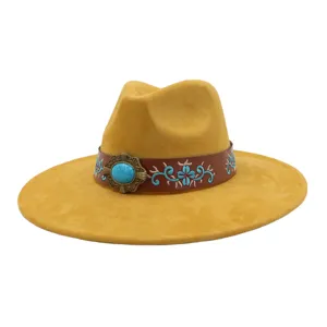 Primer plano del sombrero fedora de ante de ala ancha, con hebilla turquesa y banda bordada.