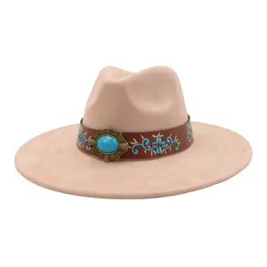 Detalle en primer plano del sombrero de ante de ala ancha, hebilla turquesa y bordado.